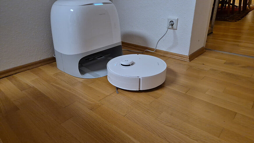 Roborock Qrevo Curv 2 Flow steht neben der weißen Station im Design test und hat davor gewischt mit der SpiraFlow-Wischwalze gleichmäßig über Parkettboden